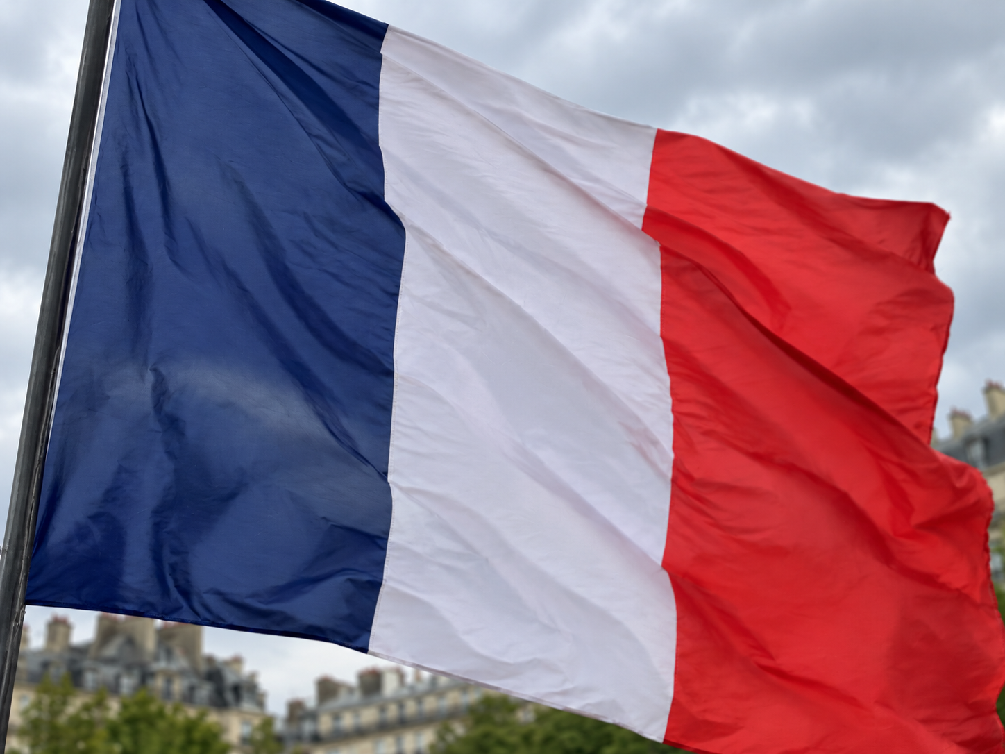A slightly blurred photo of the French flag in a city square